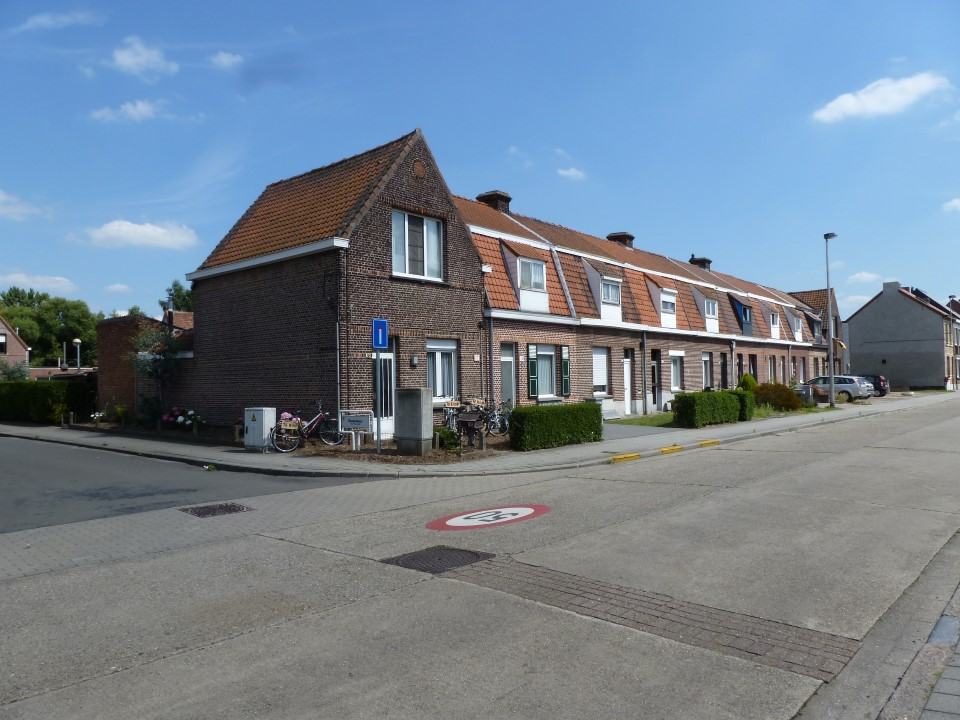 Een straat met rijwoningen in rode baksteen in het Ganzenkoor in Duffel, onder een blauwe lucht